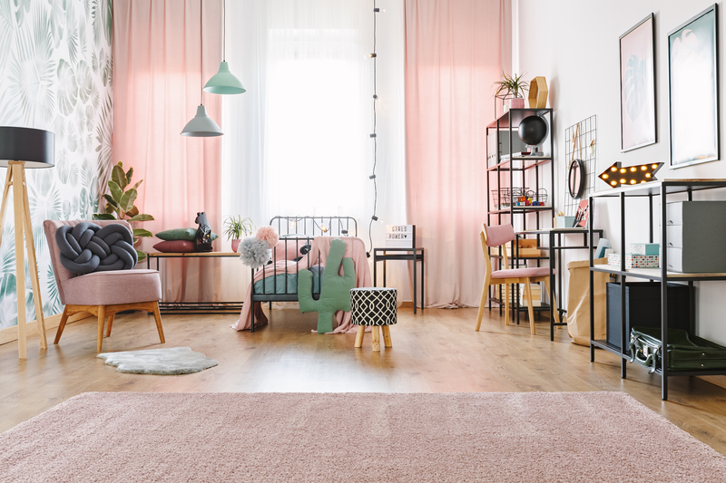 Windows with white and pink curtains in with lamps, pink chairs and soft carpet